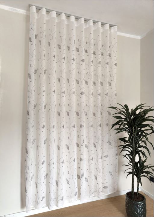 Immagine di eleganti tende a onda Wave su misura, realizzate in tessuto bianco 100% poliestere con ricamo floreale calla grigio/bianco, complete di un binario in alluminio satinato, ideale per un design raffinato e moderno.