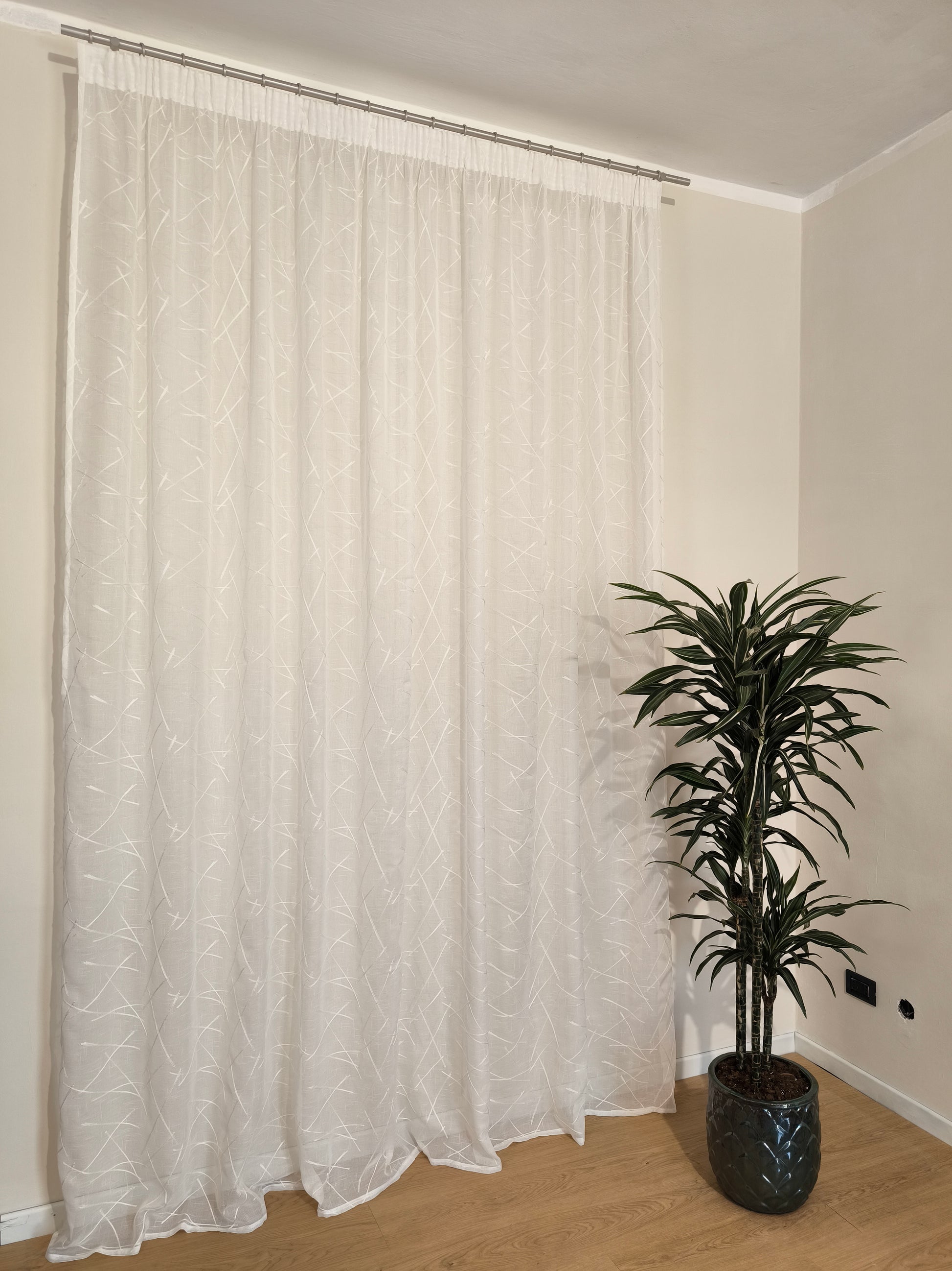 Rideau blanc naturel avec broderie ton sur ton sur tissu de rideau.