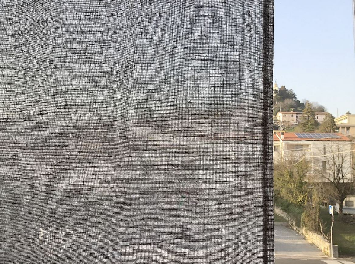 Tessuto grigio effetto lino semitrasparente.