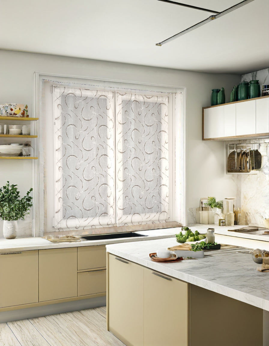 Coppia di tende bianche e marroni con fantasia geometrica su tessuto effetto lino, montate su finestra in cucina.