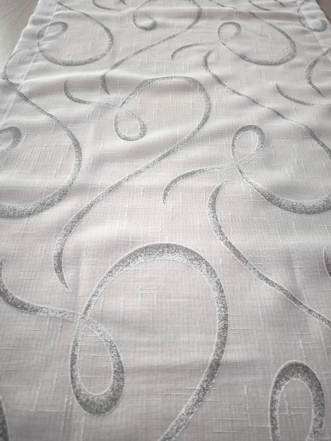 Zoom su tessuto tenda effetto lino con stampa geometrica nei toni del bianco e grigio.