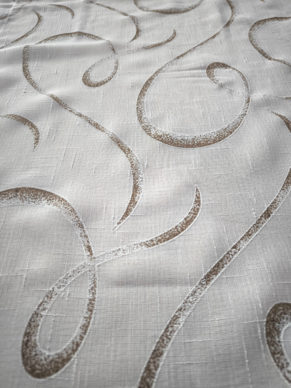 Zoom su tessuto tenda effetto lino con stampa geometrica nei toni del bianco e marrone.
