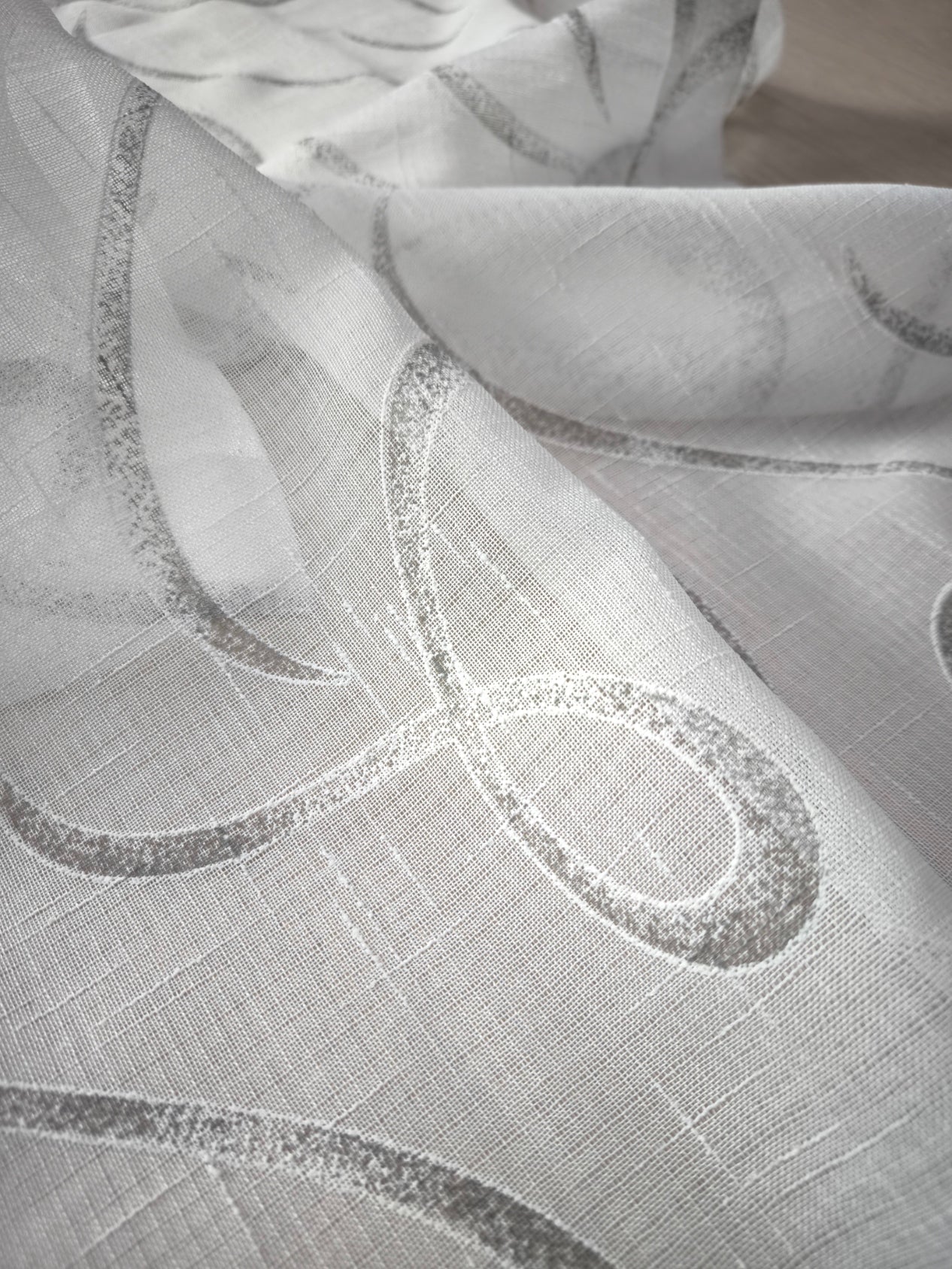 Dettaglio tessuto tenda effetto lino bianco e grigio con fantasia geometrica.