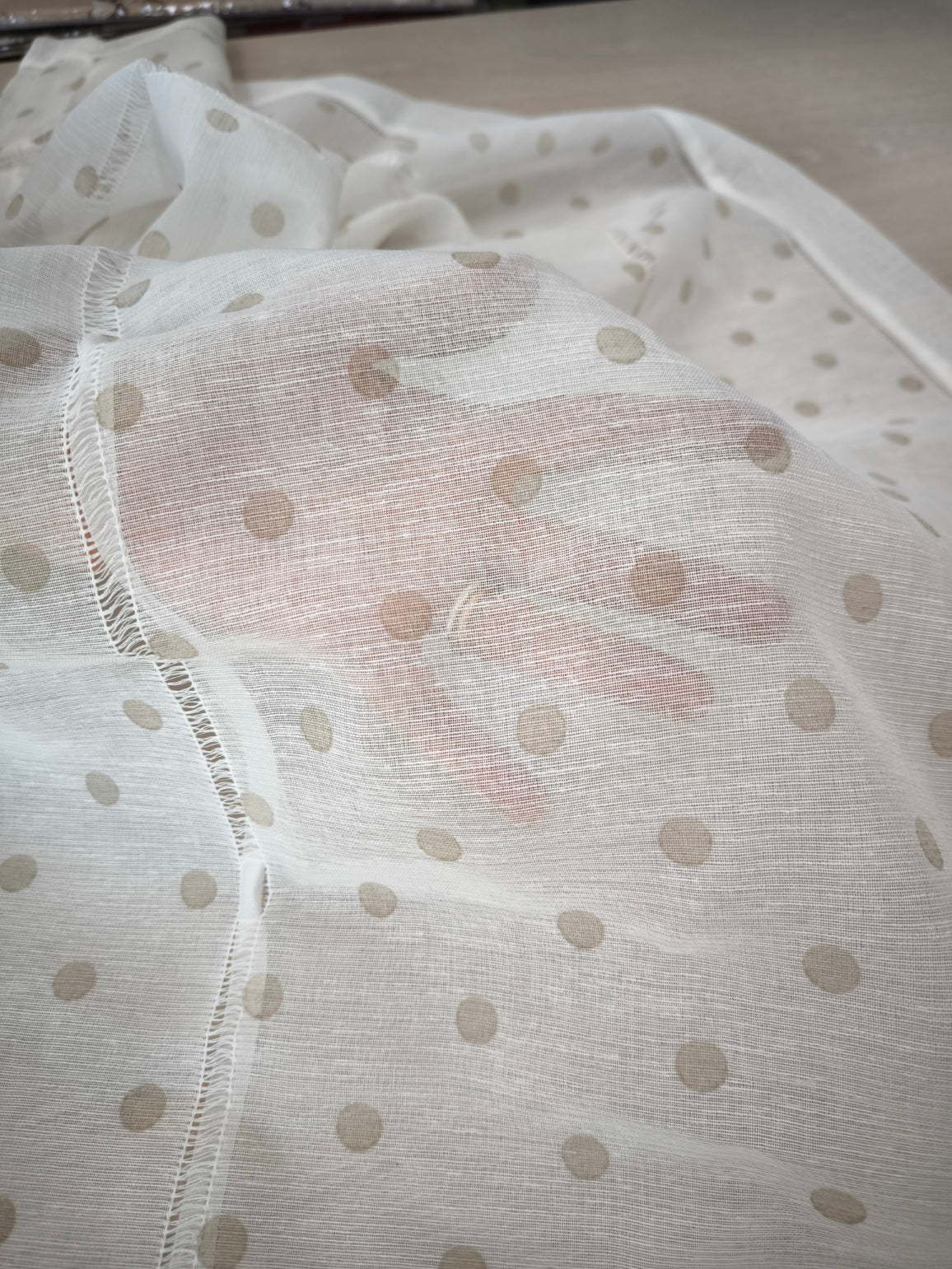 Una mano posta dietro il tessuto della tenda, che mette in evidenza la sua trasparenza e leggerezza.