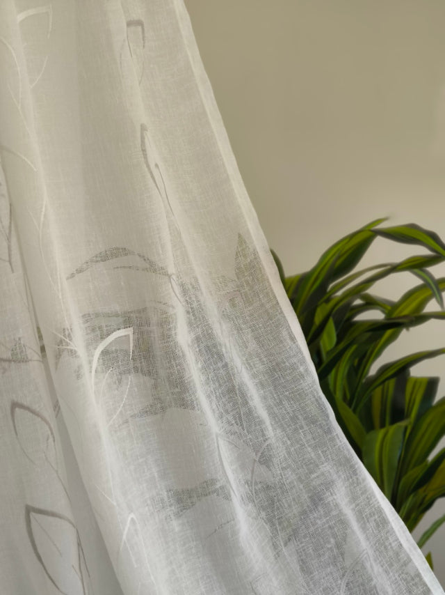 Dettaglio della trasparenza del tessuto della tenda bianca naturale con ricamo.