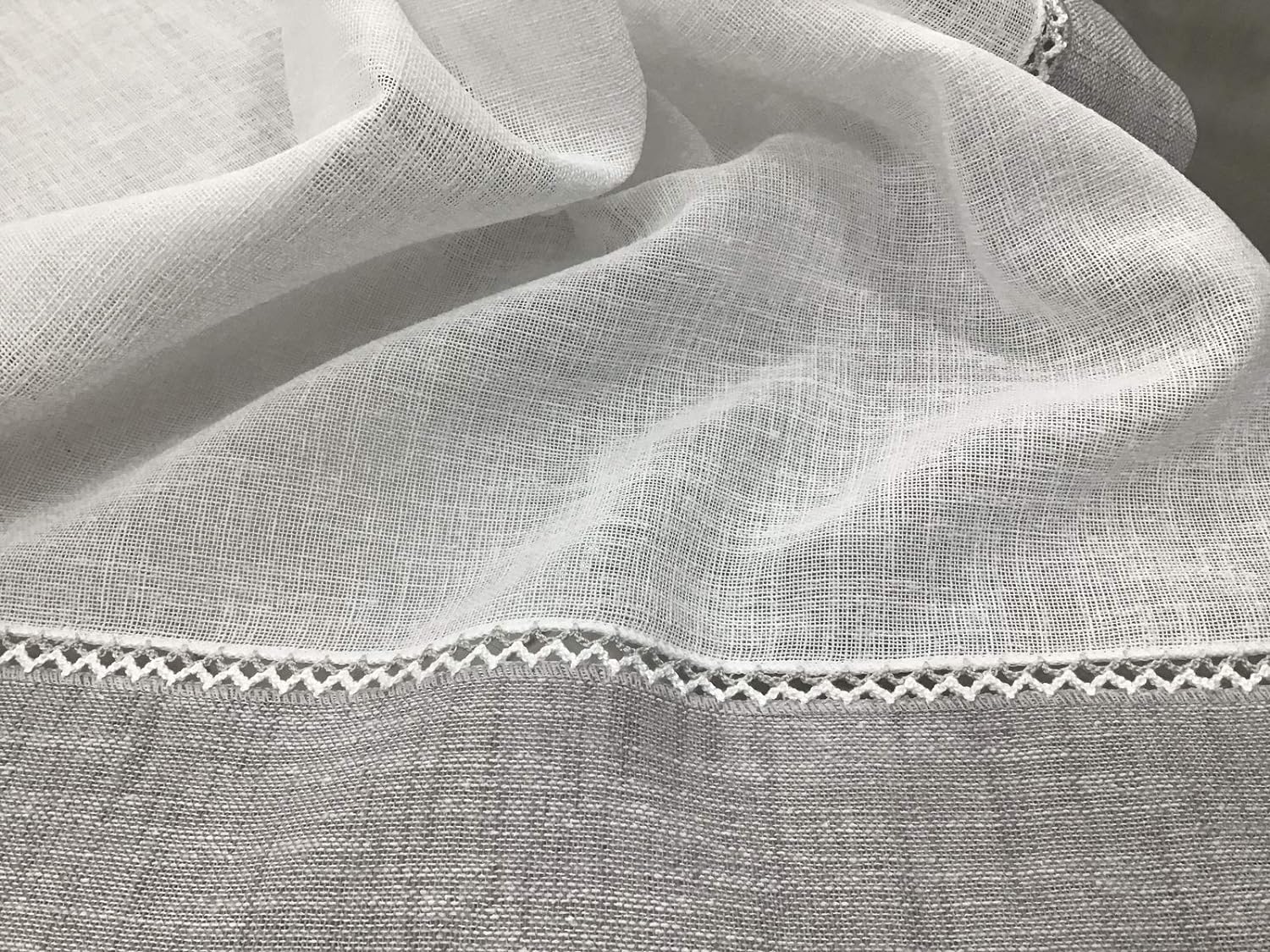 Dettaglio del tessuto effetto lino bianco naturale con bordo grigio e fissaggio con crochetta
